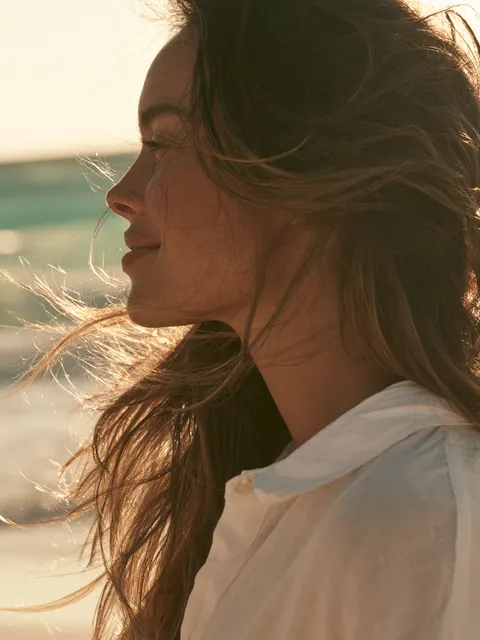 Imagen ilustrativa de rinoplastia: modelo en la playa al atardecer